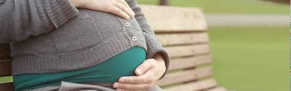 Pregnant woman sitting on a bench, holding her rounded stomach